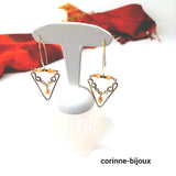 Boucles d'oreilles pendantes de forme géométrique en triangle avec chaine acier doré et perles en verre orange. Bijou fait main et unique.