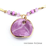 Collier avec pendentif en céramique peinte à la main couleur violet et bordure dorée à la forme ondulée. Collier monté sur chaine torsadée dorée en acier inoxydable. Perles en verre violet et mauve. Collier unique fait main à Beynes dans les Yvelines.