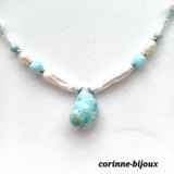 Gros plan sur le pendentif en larimar bleu turquoise en forme de goutte, accompagné de perles d'eau douce blanches et de perles turquoise.